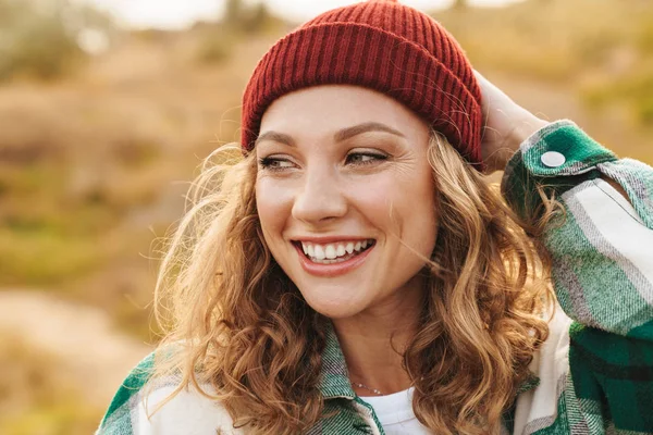 Obrázek mladé ženy v klobouku a kostkované košili chůze venku — Stock fotografie
