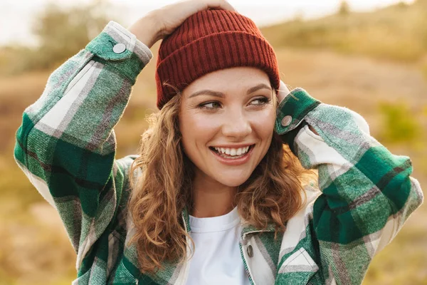 Image de jeune femme portant chapeau et chemise à carreaux marchant en plein air — Photo