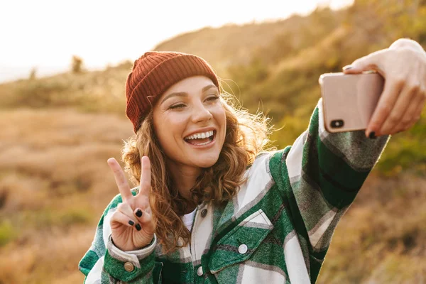 Зображення жінки, яка фотографує селфі на мобільному телефоні під час ходьби — стокове фото