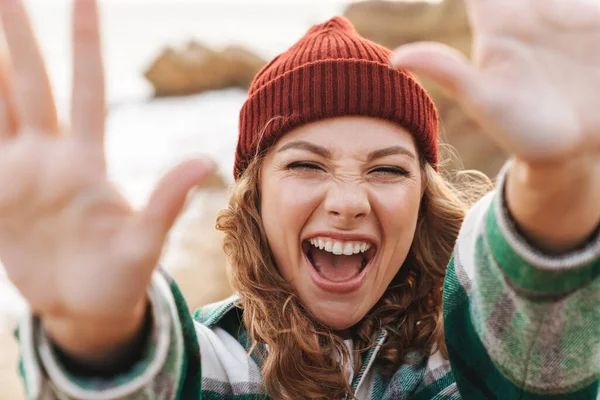 Image of young woman reaching hands at camera while walking outd