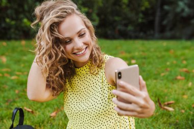 Doğa parkında mutlu bir kadın selfie çekiyor.
