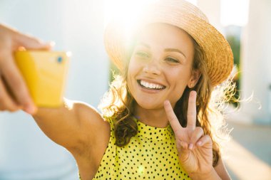 Sokaktan sokağa yürüyen bir kadın selfie çekiyor.