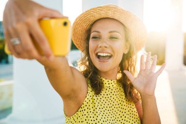 Sokaktan sokağa yürüyen bir kadın selfie çekiyor.
