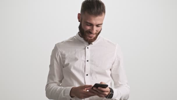 Positive Young Bearded Man Wearing White Shirt Using His Phone — Stock Video