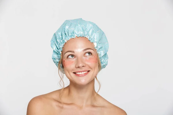 Image of woman wearing cosmetic patches and shower cap looking upward — Stock Photo, Image