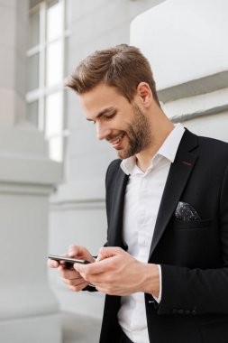 Şehirde duran takım elbiseli yakışıklı genç işadamı.