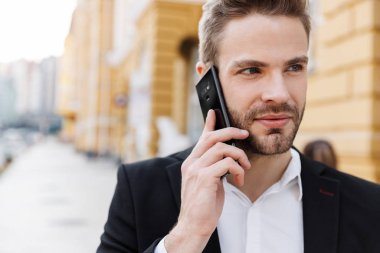 Şehirde duran takım elbiseli yakışıklı genç işadamı.