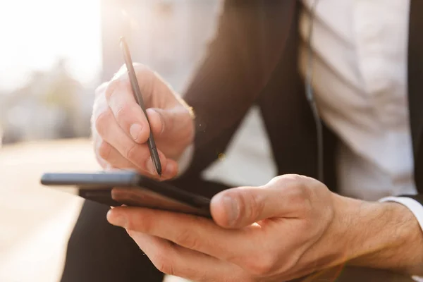 Primer plano de un hombre de negocios usando teléfono móvil y lápiz — Foto de Stock