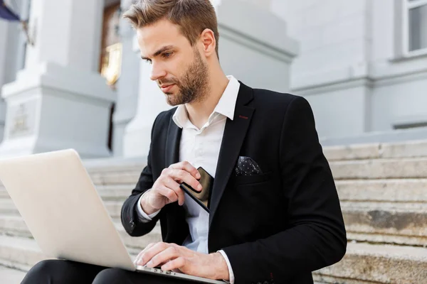 Attractive young businessman wearing suit using mobile phone — Stock Photo, Image