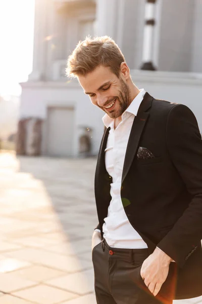Schöner junger lächelnder Geschäftsmann, der in der Stadt steht — Stockfoto
