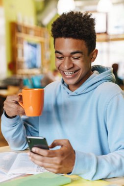 Gülümseyen Afrikalı robot genç, merkezde otururken ders çalışıyor.