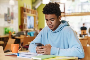 Gülümseyen Afrikalı robot genç, merkezde otururken ders çalışıyor.