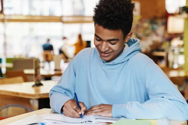 Sorrindo Africano bot adolescente estudando enquanto sentado no cubo — Fotografia de Stock