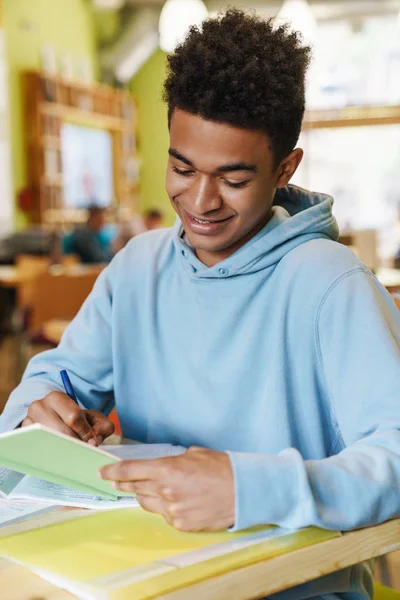 Sorrindo Africano bot adolescente estudando enquanto sentado no cubo — Fotografia de Stock