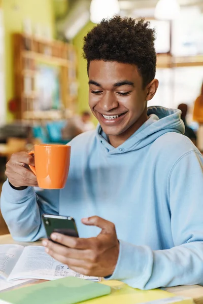 Gülümseyen Afrikalı robot genç, merkezde otururken ders çalışıyor.
