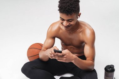 Afro-Amerikan bir adamın otururken cep telefonu ve kulaklık kullandığı fotoğraf.