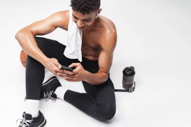 Afro-Amerikan bir adamın otururken cep telefonu ve kulaklık kullandığı fotoğraf.