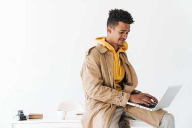 Kafası karışmış Afro-Amerikan bir adamın laptopta otururken daktilo yazması.