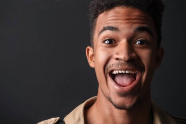 Heyecanlı Afrikalı Amerikalı bir adamın gülümseyen ve kameraya bakan fotoğrafı.