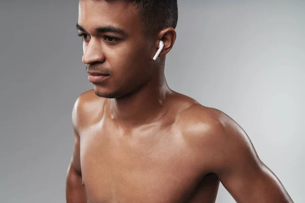 Zbliżenie zdjęcia afrykańskiego mężczyzny bez koszulki, używającego słuchawki. — Zdjęcie stockowe