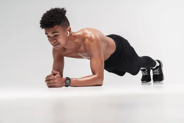 Foto de hombre afroamericano usando auriculares y haciendo ejercicio — Foto de Stock