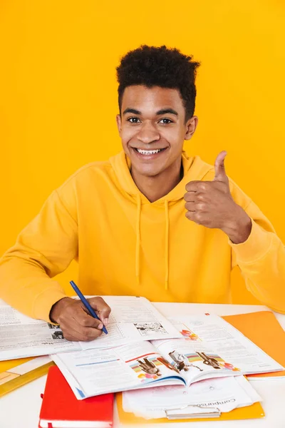 Menino adolescente africano feliz estudando enquanto sentado na mesa — Fotografia de Stock