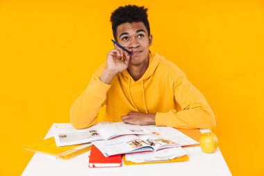 Mutlu Afrikalı genç çocuk masada otururken ders çalışıyor.