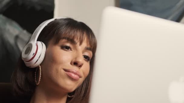 Όμορφη Καυκάσια Νεαρή Γυναίκα Ακουστικά Που Εργάζονται Ένα Φορητό Υπολογιστή — Αρχείο Βίντεο