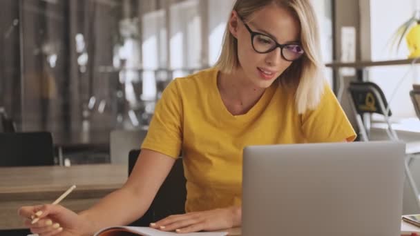 Een Leuke Jonge Vrouw Met Een Bril Schrijft Haar Notitieboekje — Stockvideo