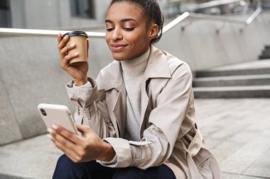 Gülümseyen genç Afrikalı kadın sonbahar ceketi giyiyor.