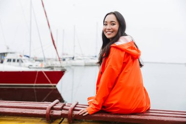 Smiling attractive young asian woman wearing raincoat