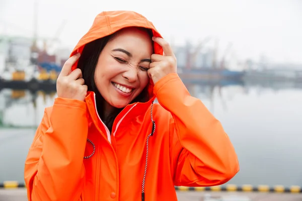 Smiling attractive young asian woman wearing raincoat — Stockfoto