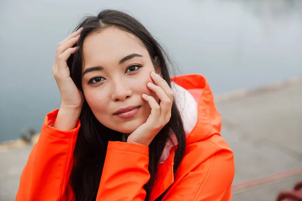 Lachende aantrekkelijke jonge aziatische vrouw dragen regenjas — Stockfoto