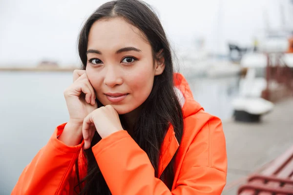 Lachende aantrekkelijke jonge aziatische vrouw dragen regenjas — Stockfoto