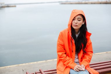 Smiling attractive young asian woman wearing raincoat