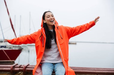 Smiling attractive young asian woman wearing raincoat