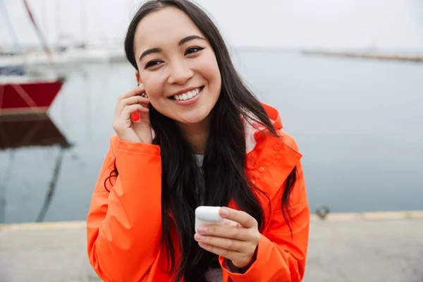 Smiling attractive young asian woman wearing raincoat — Stockfoto