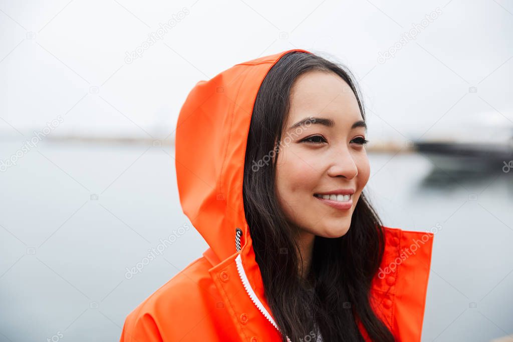 Smiling attractive young asian woman wearing raincoat