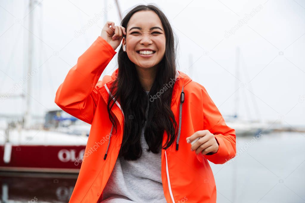 Smiling attractive young asian woman wearing raincoat