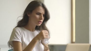 Concentrated stressful young woman is using laptop computer indoors