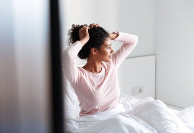 Smiling beautiful young african woman sitting in bed