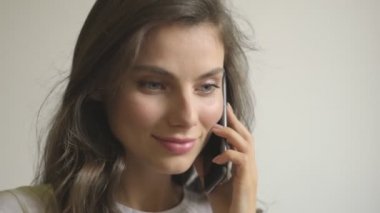 Kamera bir kadından uzaklaşıyor. İçeriden bir telefon görüşmesi yapıyor.