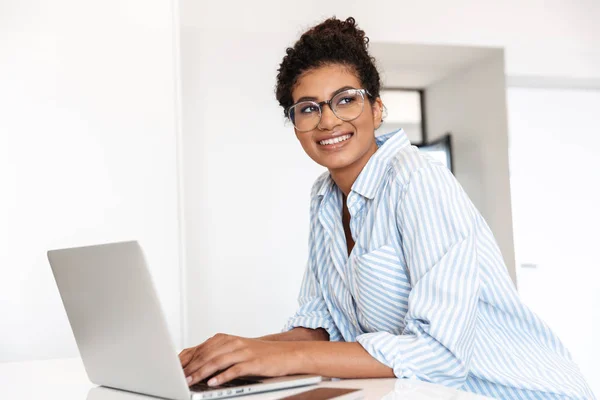 Jovem mulher africana atraente trabalhando no computador portátil — Fotografia de Stock