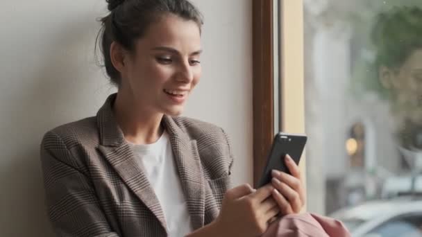 Uma Jovem Mulher Sorridente Atraente Está Usando Seu Smartphone Enquanto — Vídeo de Stock