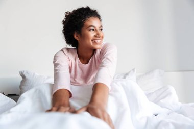 Smiling beautiful young african woman sitting in bed