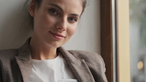 Una Mujer Sonriente Relajada Está Sentada Alféizar Ventana Mirando Cámara — Vídeos de Stock