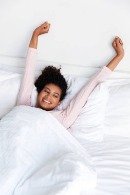 Smiling beautiful young african woman laying in bed in the morning