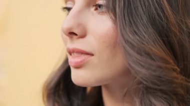 Güzel bir kadının yakın çekim görüntüsü, dışarıda dururken yana ve kameraya bakıyor.