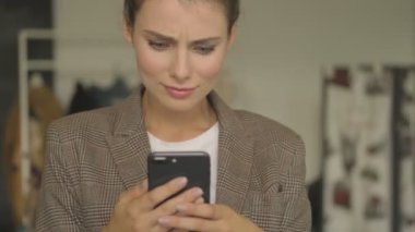 Kafası karışmış genç bir iş kadını kapalı alanda akıllı telefonunda bir şey arıyor.