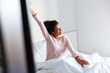 Smiling beautiful young african woman sitting in bed